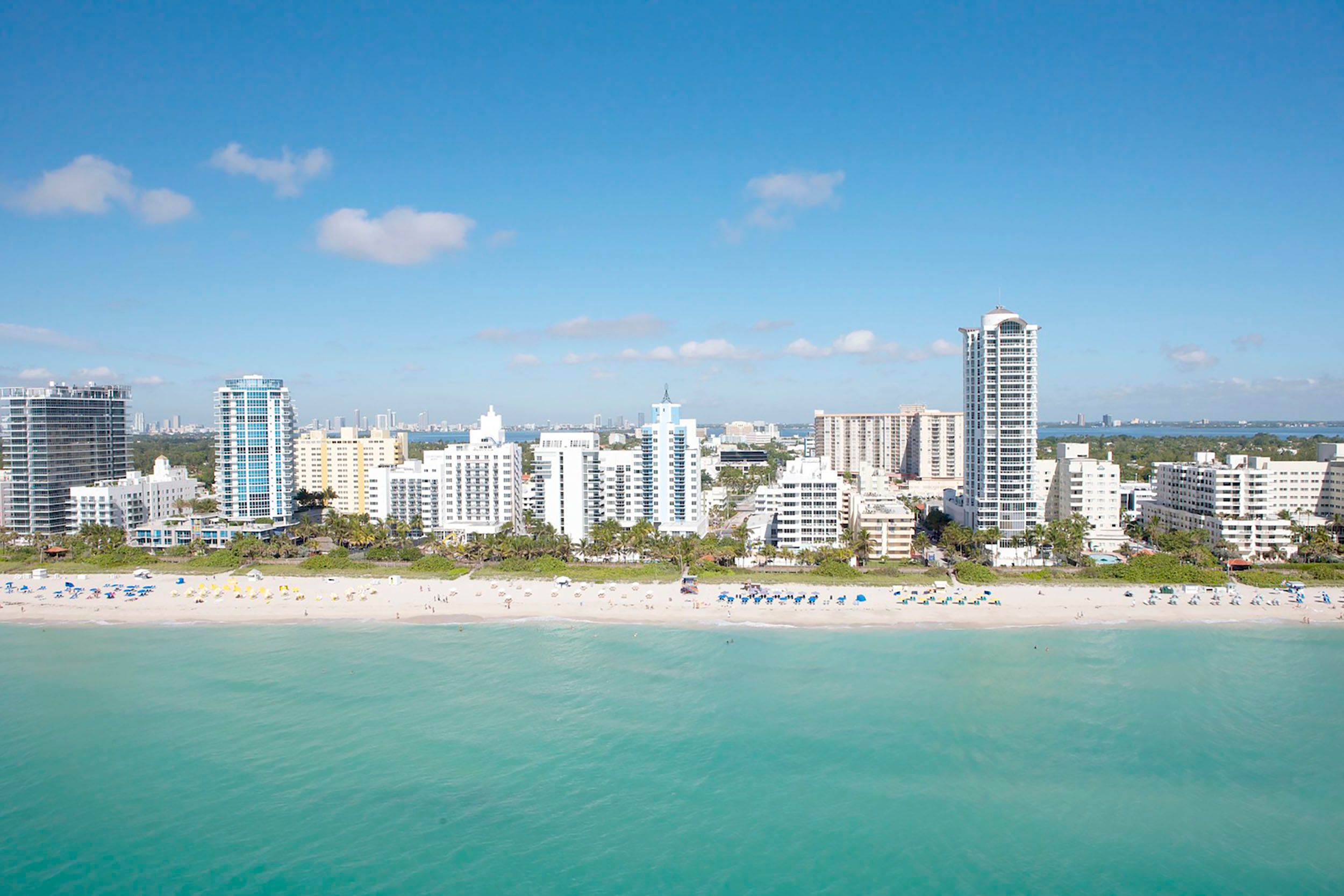 Aerial view of Miami Beach buildings, white sand, and turquoise ocean